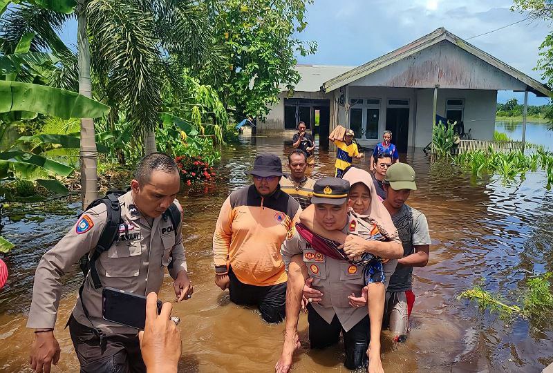 Foto----Kapolsek MHS menggendong seorang nenek untuk melewati genangan air di Desa Sungai Pelang----Humas Polres Ketapang.