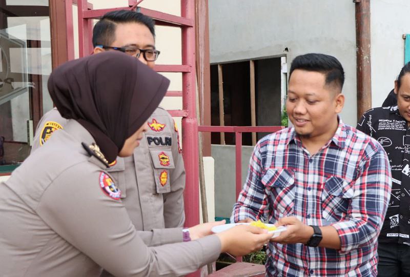 Foto---Kasi Humas Polres, IPTU Laury Tessalonica Lawdia menyerahkan potongan tumpeng kepada Ketua AJK, Theo Bernadhi usai syukuran, Senin (31/10/2022)--Humas.