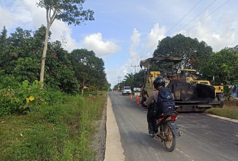 Foto---Proses pengerjaan jalan di Sumber Periangan. Tampak pengendara melintasi jalan yang sudah di aspal--- Abdul