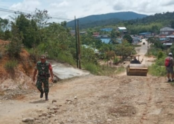 Sertu Budiyono Babinsa Kodim 1206 Putussibau Koramil 11/Silat Hilir saat membantu perbaiki jalan